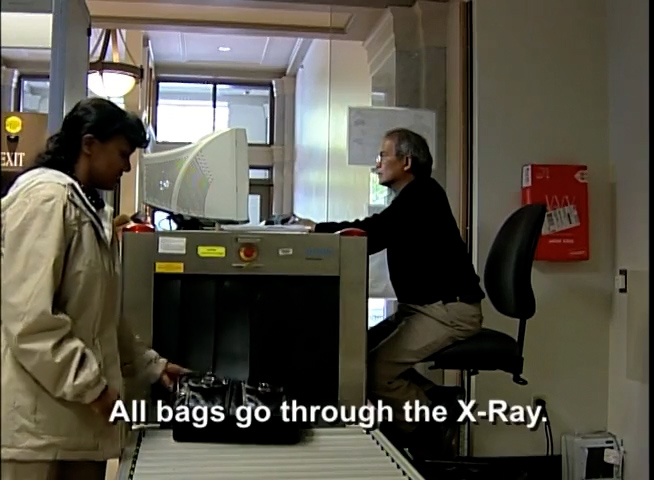 Woman picks up her bag from courthouse x-ray machine.